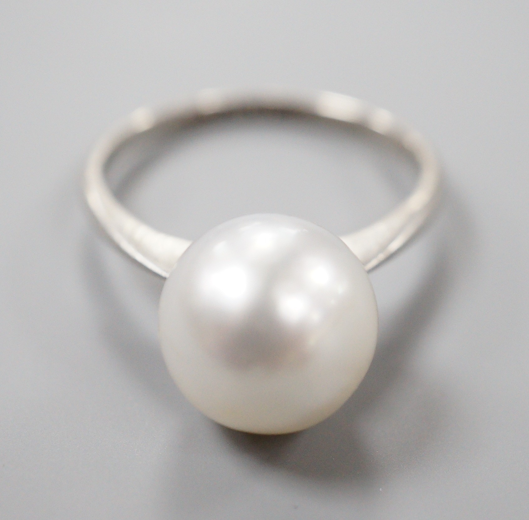 A white metal (stamped Plat) and single stone cultured pearl ring, size O, gross weight 4.1 grams.